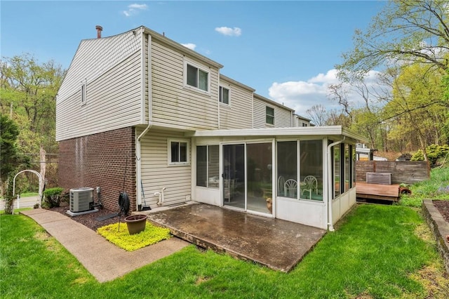 rear view of house featuring a sunroom, a patio, cooling unit, a lawn, and brick siding