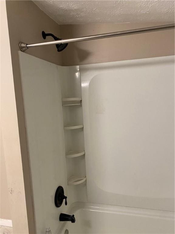 bathroom with a textured ceiling and tub / shower combination