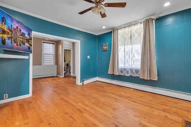 empty room with a baseboard heating unit, ceiling fan, crown molding, baseboard heating, and hardwood / wood-style flooring