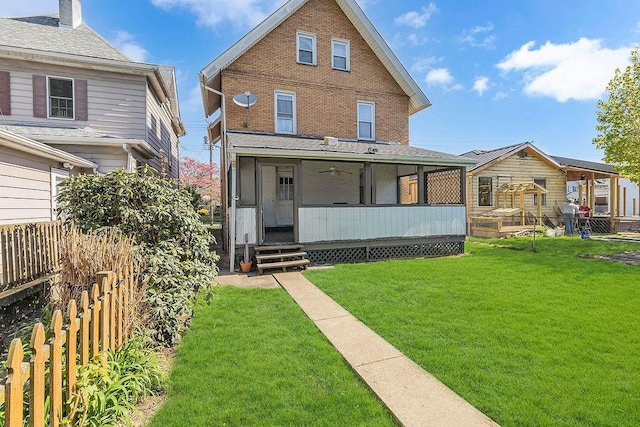 back of property featuring fence, a yard, and brick siding