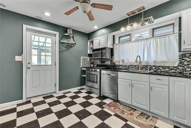 kitchen with tile patterned floors, stainless steel appliances, dark countertops, backsplash, and a sink