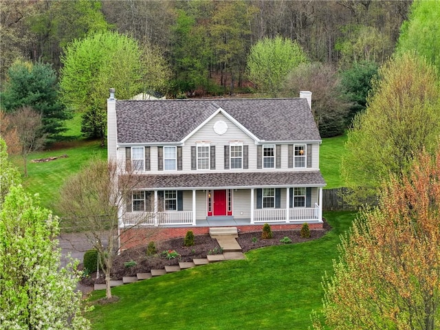 view of front of property with a front yard, a chimney, a porch, and a shingled roof