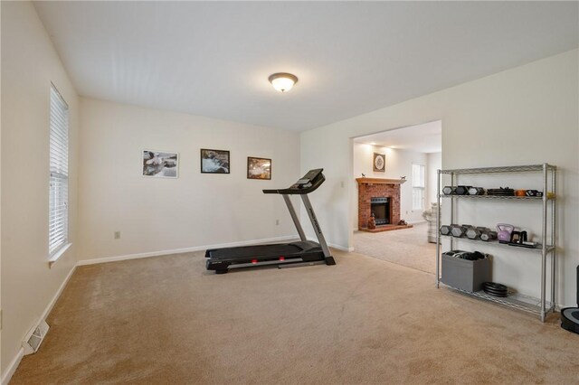 exercise area with a brick fireplace, a wealth of natural light, and carpet floors