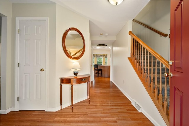 corridor with visible vents, light wood-type flooring, and stairs