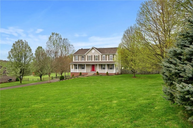 colonial home with a front lawn, fence, covered porch, and brick siding