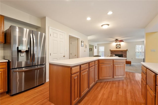 kitchen with stainless steel refrigerator with ice dispenser, a ceiling fan, light wood-style floors, and light countertops