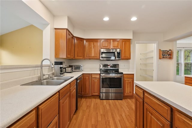 kitchen featuring recessed lighting, appliances with stainless steel finishes, light countertops, a sink, and light wood-type flooring