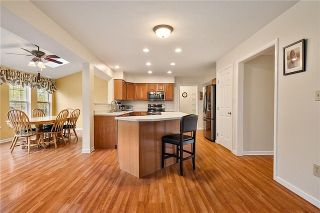kitchen featuring appliances with stainless steel finishes, brown cabinets, light countertops, and baseboards