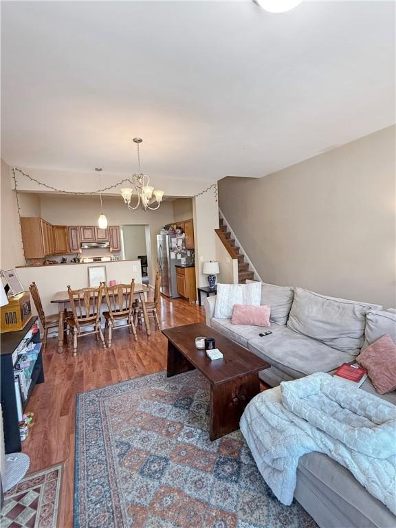 living room featuring a chandelier, stairway, and wood finished floors