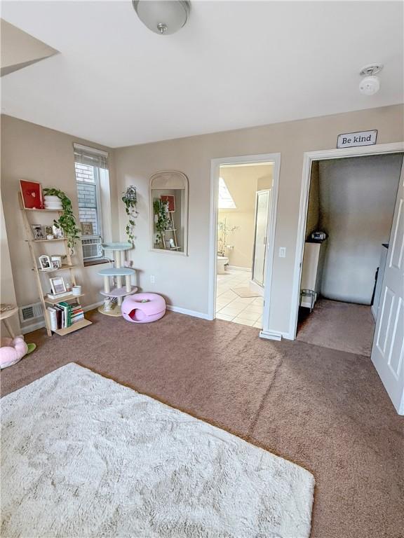 bedroom featuring baseboards, ensuite bath, and carpet