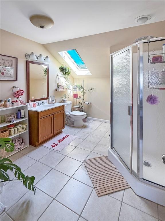 full bath featuring tile patterned floors, a skylight, a shower stall, and vanity