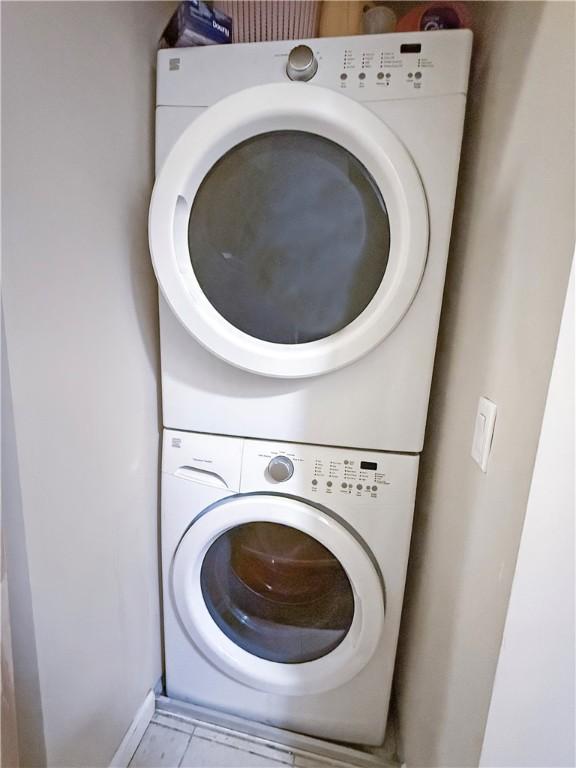 laundry area with stacked washer and dryer, tile patterned flooring, and laundry area