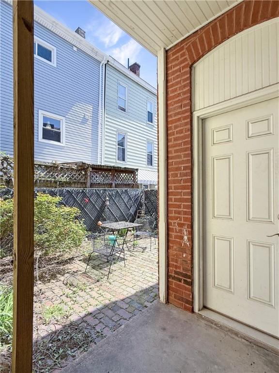 doorway to property with a patio, brick siding, fence, and outdoor dining space