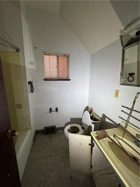 bathroom with visible vents, toilet, vaulted ceiling, vanity, and tile patterned flooring