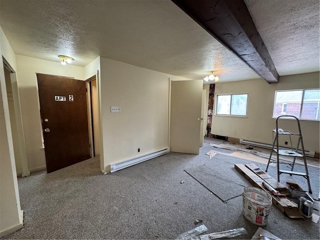 carpeted spare room with a baseboard heating unit, a textured ceiling, and beam ceiling