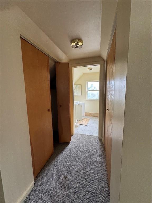 hallway with light carpet and lofted ceiling