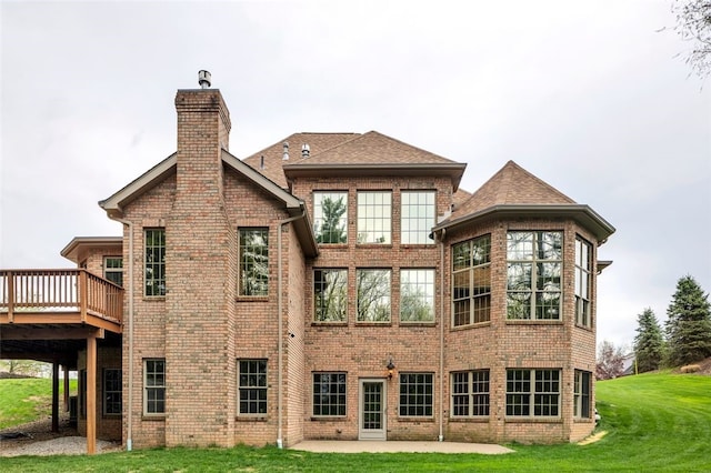 rear view of house featuring a wooden deck, brick siding, a patio area, a lawn, and a chimney