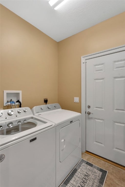 washroom featuring light tile patterned floors, washing machine and clothes dryer, and laundry area