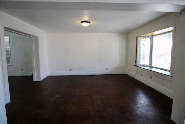 spare room featuring dark wood finished floors and baseboards