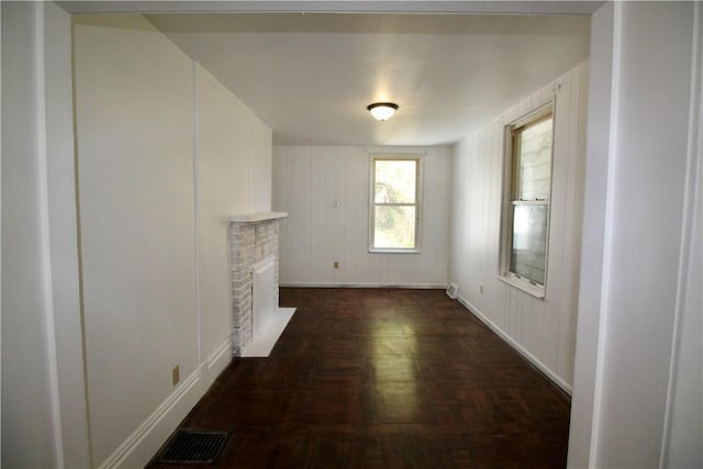 unfurnished living room featuring visible vents, baseboards, and a brick fireplace