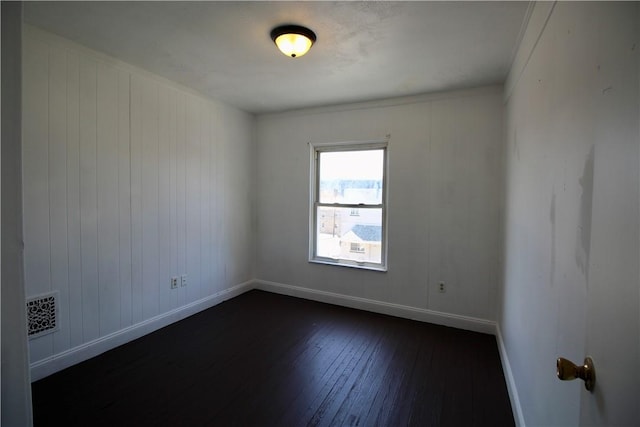 spare room featuring visible vents, dark wood-style floors, and baseboards