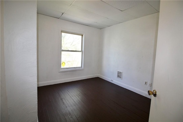 empty room featuring baseboards, visible vents, dark wood-style floors, and a paneled ceiling