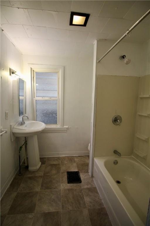 bathroom featuring toilet, baseboards, bathtub / shower combination, and a sink