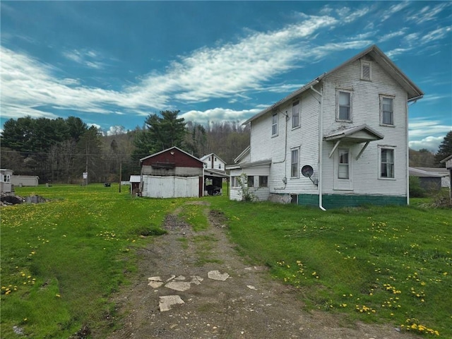 view of side of property with dirt driveway and a lawn