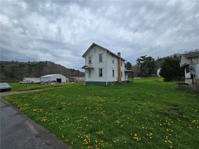 view of side of home featuring a chimney and a lawn