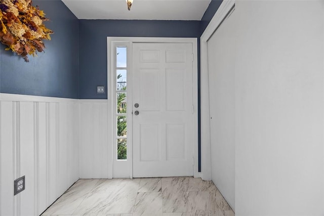 entryway with marble finish floor and wainscoting
