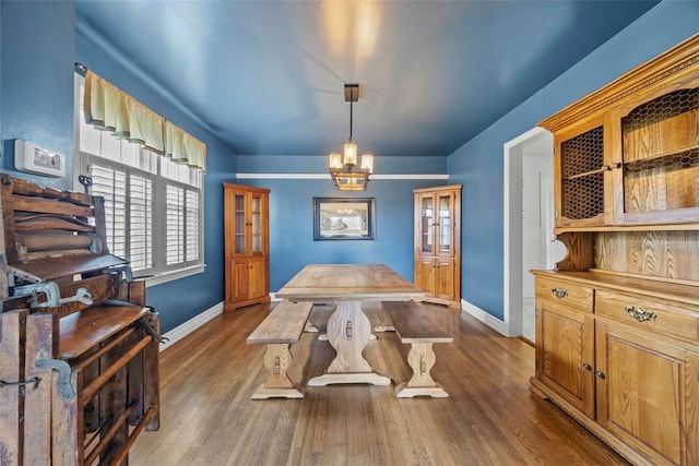 dining area featuring a notable chandelier, dark wood finished floors, and baseboards
