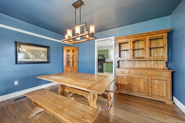 dining space featuring a chandelier, baseboards, and dark wood-style flooring
