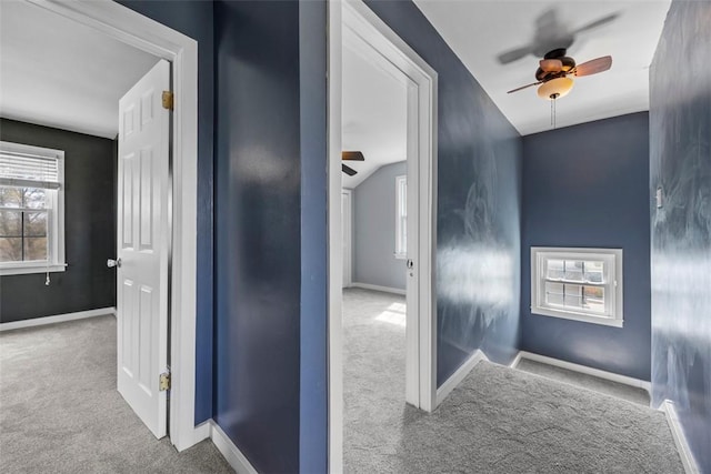 corridor featuring lofted ceiling, carpet, a wealth of natural light, and baseboards