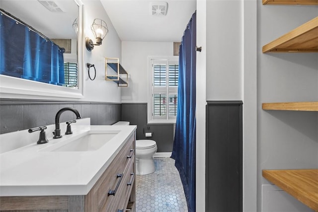 full bath with visible vents, a wainscoted wall, toilet, tile patterned floors, and vanity
