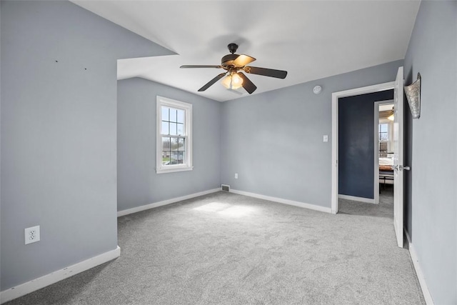 carpeted empty room with ceiling fan, visible vents, and baseboards