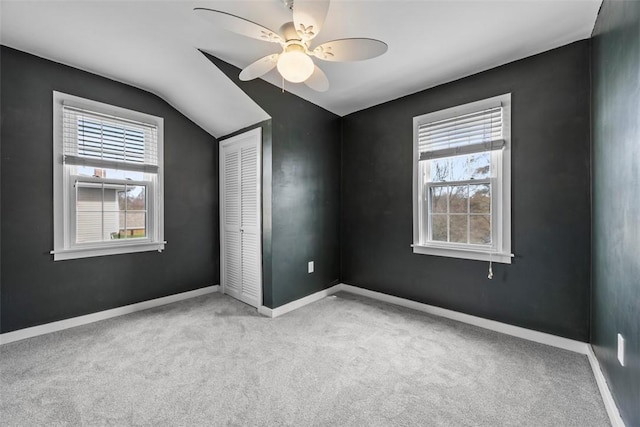 unfurnished bedroom with lofted ceiling, carpet, baseboards, and a closet