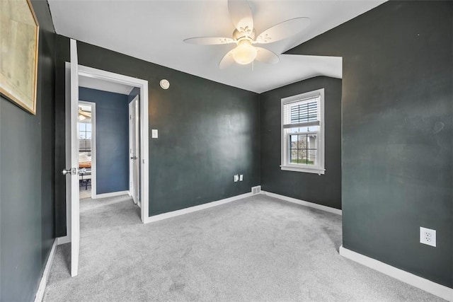empty room featuring carpet, visible vents, a ceiling fan, and baseboards