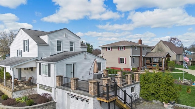 back of property featuring roof with shingles, stairs, a residential view, and a garage
