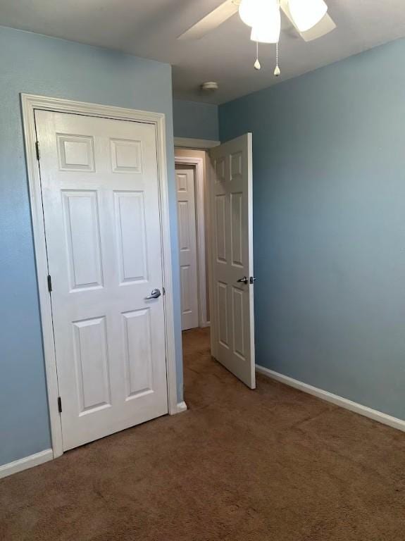 unfurnished bedroom featuring baseboards, ceiling fan, carpet floors, and a closet