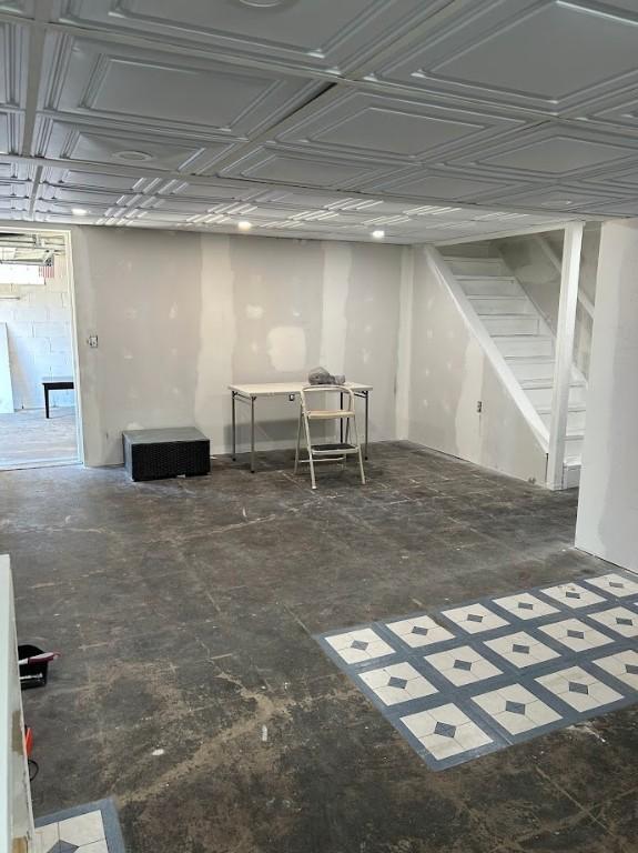 basement with an ornate ceiling and stairs