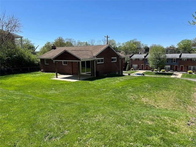 rear view of house featuring a patio, brick siding, and a yard