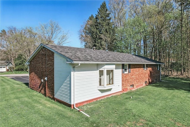 exterior space with a shingled roof and a lawn