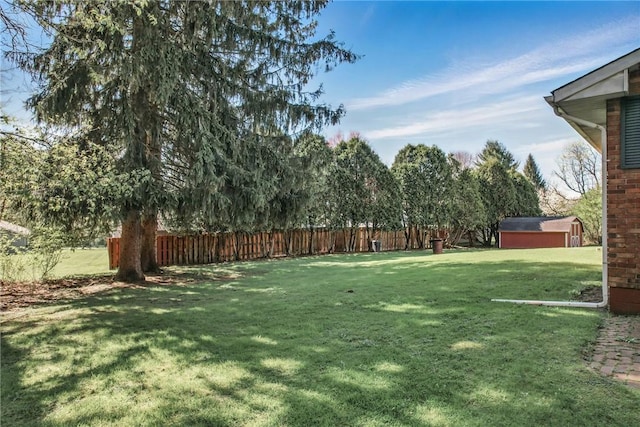 view of yard with an outbuilding, a storage shed, and fence