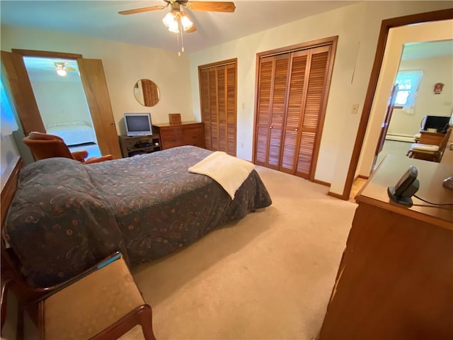 carpeted bedroom featuring baseboards, ceiling fan, multiple closets, and a baseboard heating unit