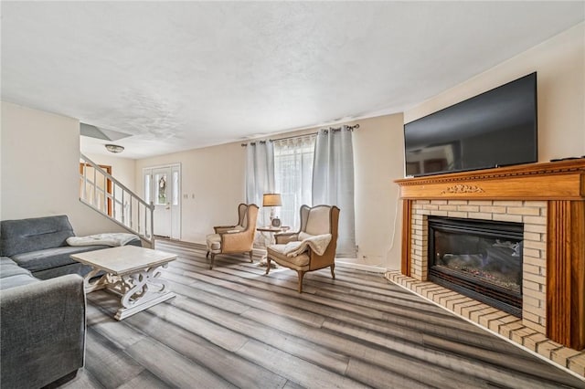 living room featuring a fireplace, wood finished floors, and stairs