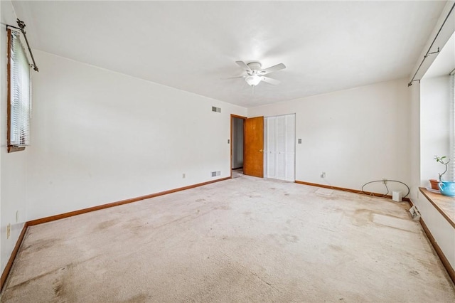 spare room with visible vents, ceiling fan, light carpet, and baseboards