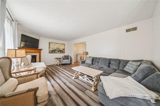 living room featuring a fireplace, wood finished floors, visible vents, and baseboards