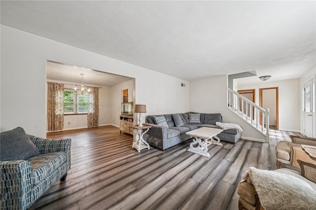 living area featuring visible vents, wood finished floors, a chandelier, baseboards, and stairway