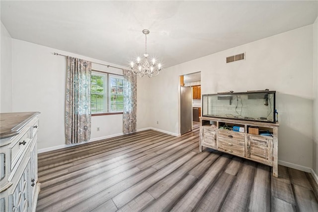 dining area featuring wood finished floors, visible vents, a notable chandelier, and baseboards