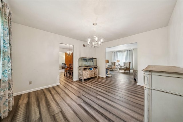 dining space featuring baseboards, visible vents, wood finished floors, and a notable chandelier